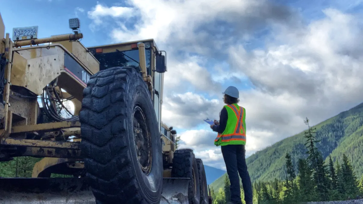 A field professional working beside heavy equipment in the Ktunaxa homelands